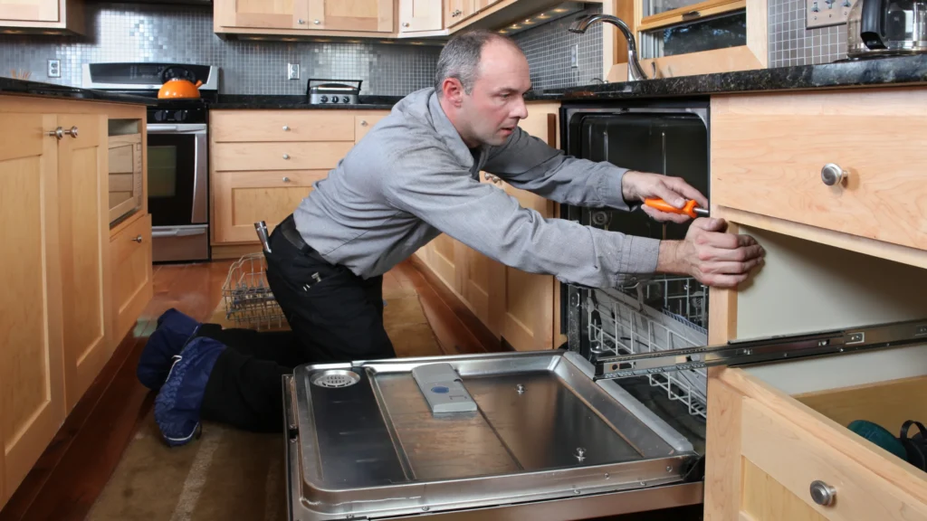 Person working at the cabinet edge beside an open built-in dishwasher