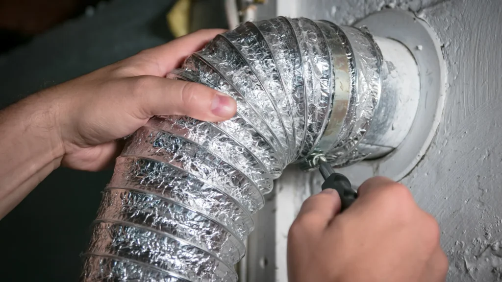 Hands positioning a flexible duct at a wall connection