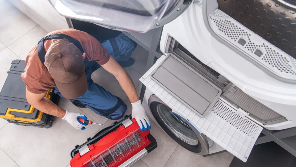 Person beside a dryer with its lower filter compartment open