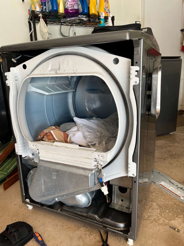 Dryer with its front panel removed, showing the drum and cabinet