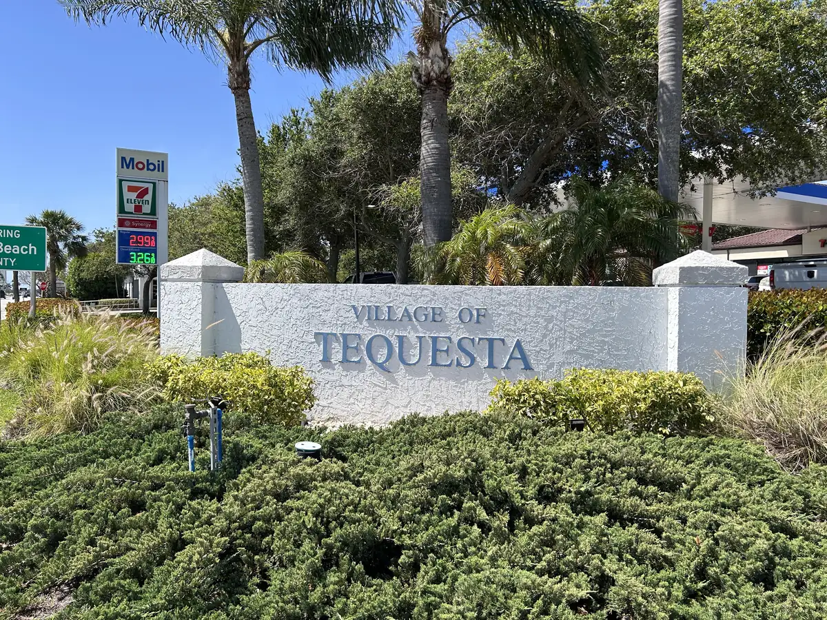 Village of Tequesta welcome sign with palms and flowering shrubs.